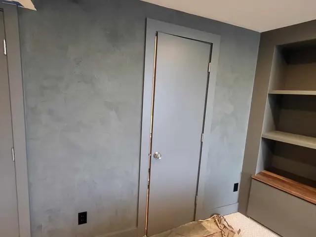 Finished slate-blue Venetian plaster accent wall framing a flush-trim door near Estacada, OR — Devine Home Remodeling & Construction
