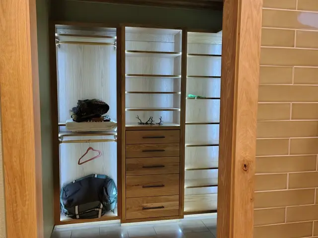 View through stained wood trim opening into illuminated custom walk-in closet near Estacada, OR — Devine Home Remodeling & Construction