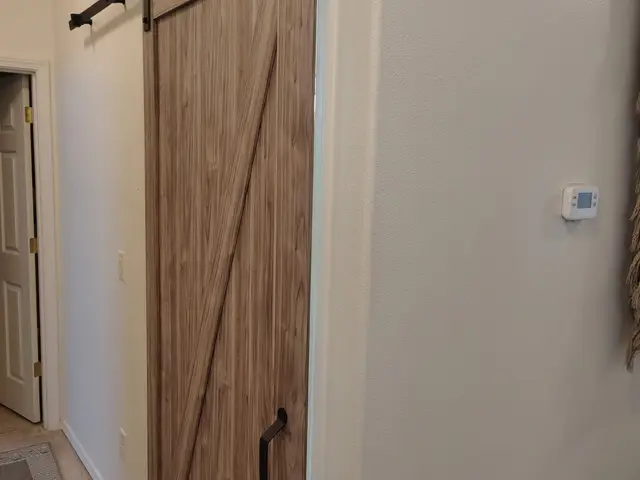 Custom wood sliding barn door with matte black hardware installed for a bathroom remodel near Estacada, OR — Devine Home Remodeling & Construction