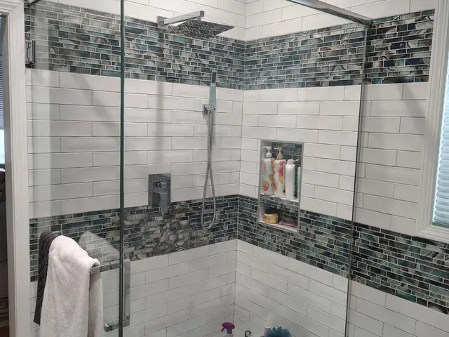 Frameless glass shower with mosaic accent band and recessed niche near Estacada, OR — Devine Home Remodeling & Construction