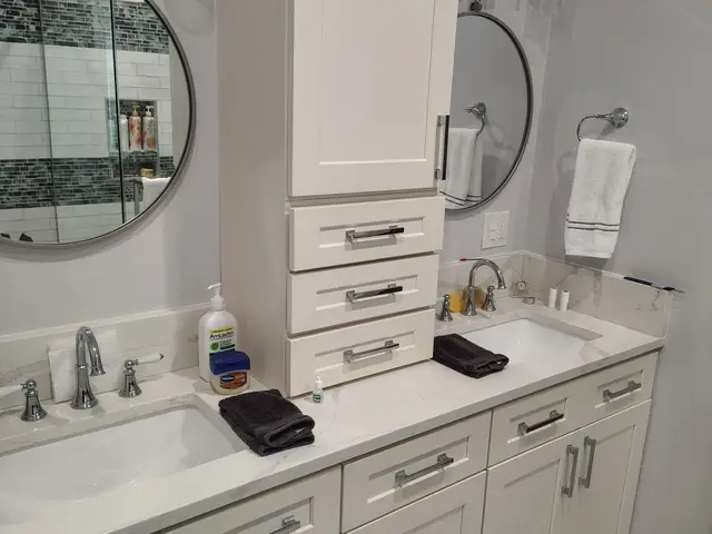 Angled view of a custom bathroom vanity with center linen tower and round mirrors near Estacada, OR — Devine Home Remodeling & Construction